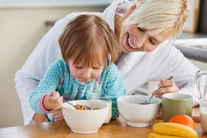 Mother and daughter eating breakfast cereal