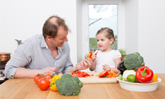 father and daughter cooking vegetables