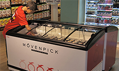 a boy chooses an ice cream from a horizontal chest freezer