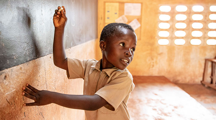 African schoolboy writing on chalkboard