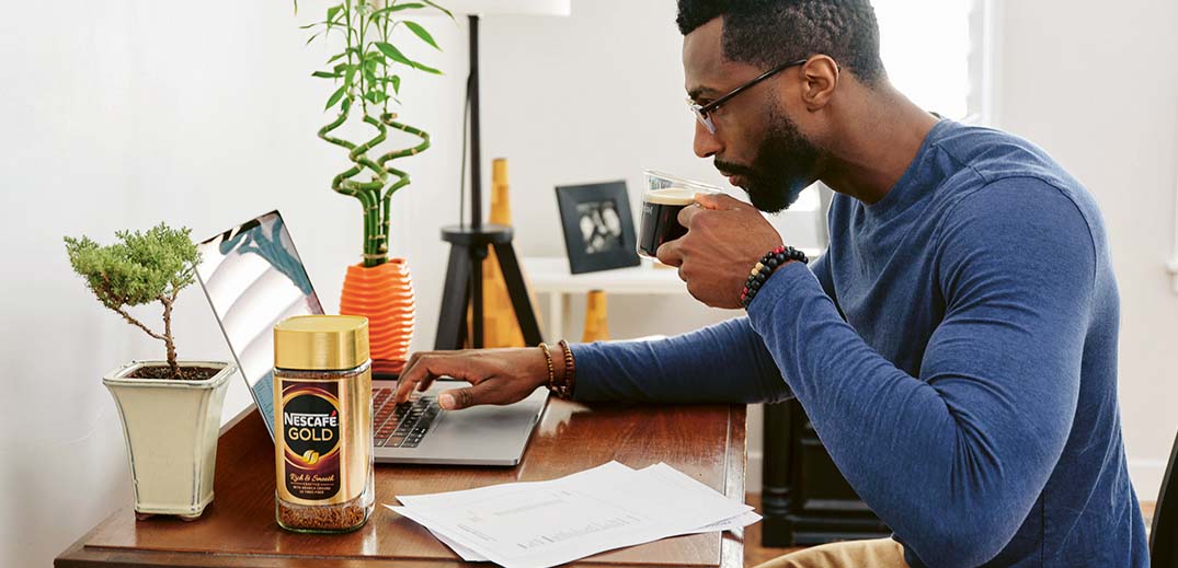 man drinking a cup of Nescafé
