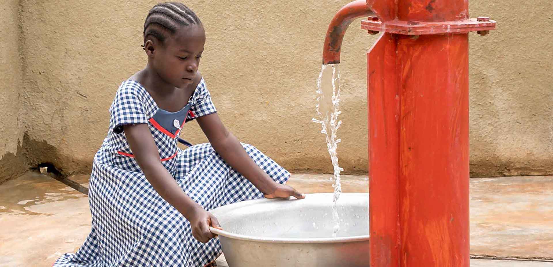 African schoolgirl using water pump