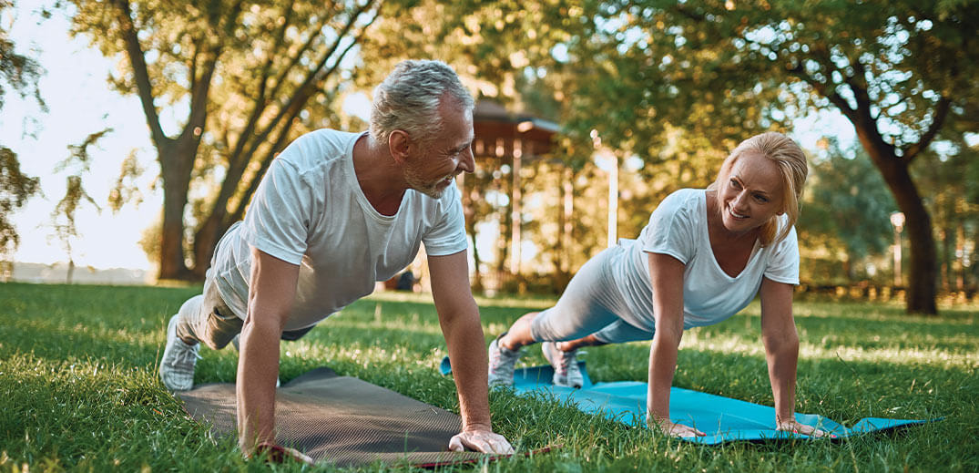 man and woman are doing a workout in the park