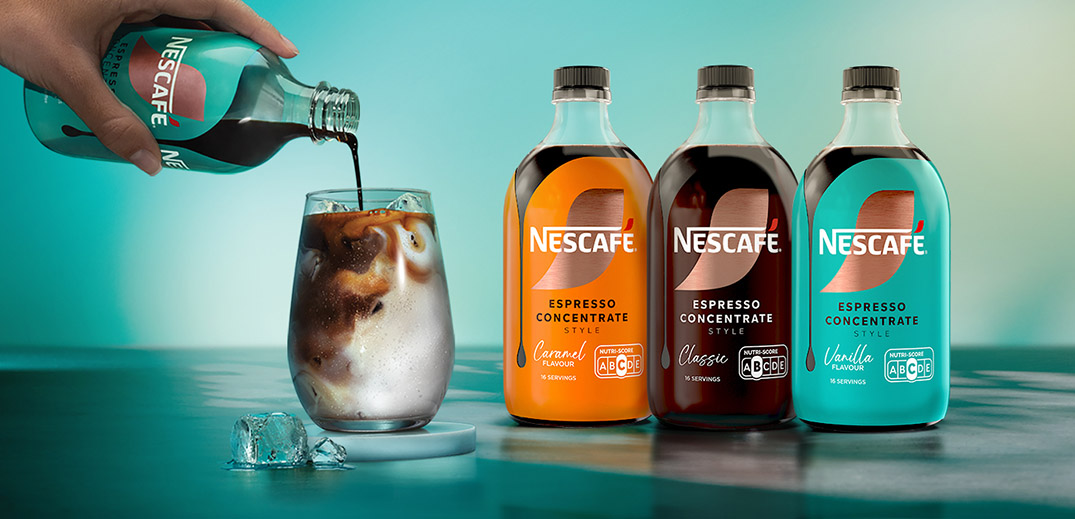 Nescafé Espresso Concentrate bottles beside an iced coffee glass as espresso concentrate is poured