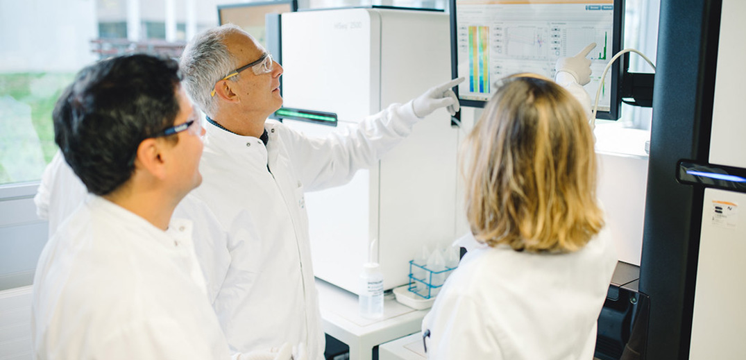 Researchers analyzing data on laboratory screens while operating advanced scientific equipment