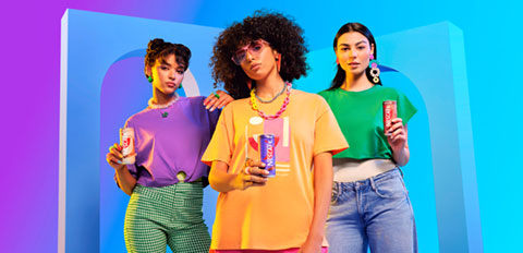 Group of friends holding colorful canned drinks against a vibrant backdrop.