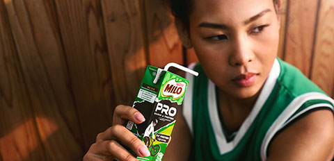 Teenager holding Milo Pro drink carton indoors