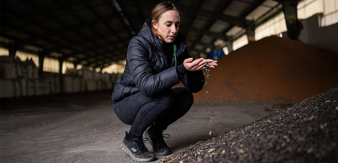 Person examining soil granules inside an agricultural storage facility for sustainable farming