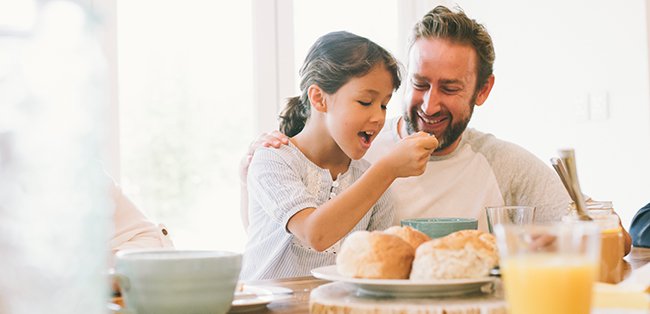 Father and daughter eating porridge for breakfast