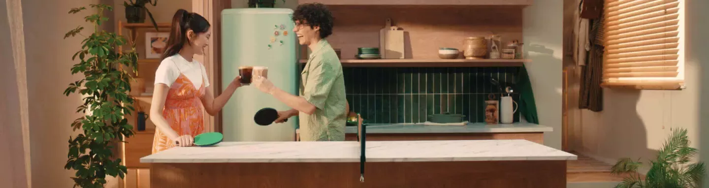 man and woman in the kitchen holding cup of coffee