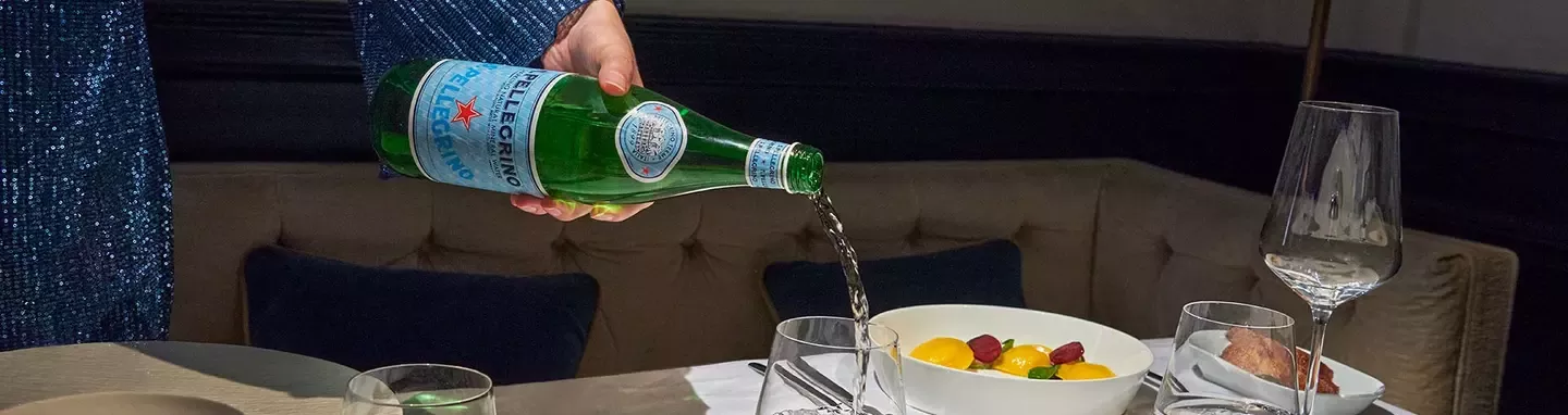 S.Pellegrino sparkling mineral water served with fine dining meal in an elegant restaurant