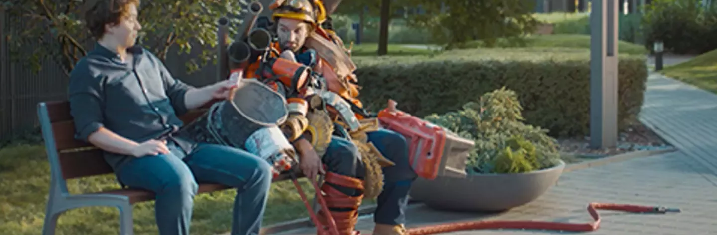 man with sticky things on him is sitting on bench in park next to man