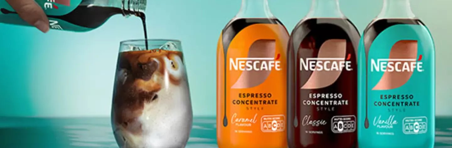 Nescafé Espresso Concentrate bottles beside an iced coffee glass as espresso concentrate is poured