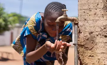 Young teenager drinking out of water fountain
