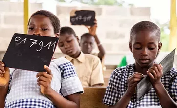 Children in the classroom holding boards above their heads