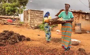 Two women carrying stuff within their African village