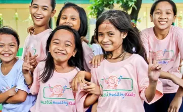 Six girls wearing pink shirts smiling at the camera