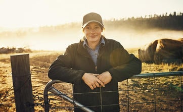 Farmer posing behind fence