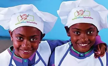 Kids in chef hats and aprons with logo