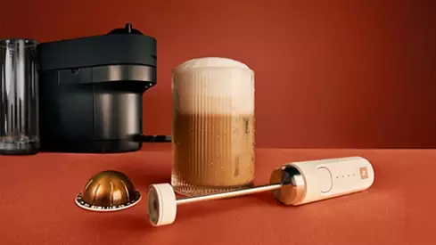 Nespresso coffee machine, milk frother and iced coffee with foam in a glass
