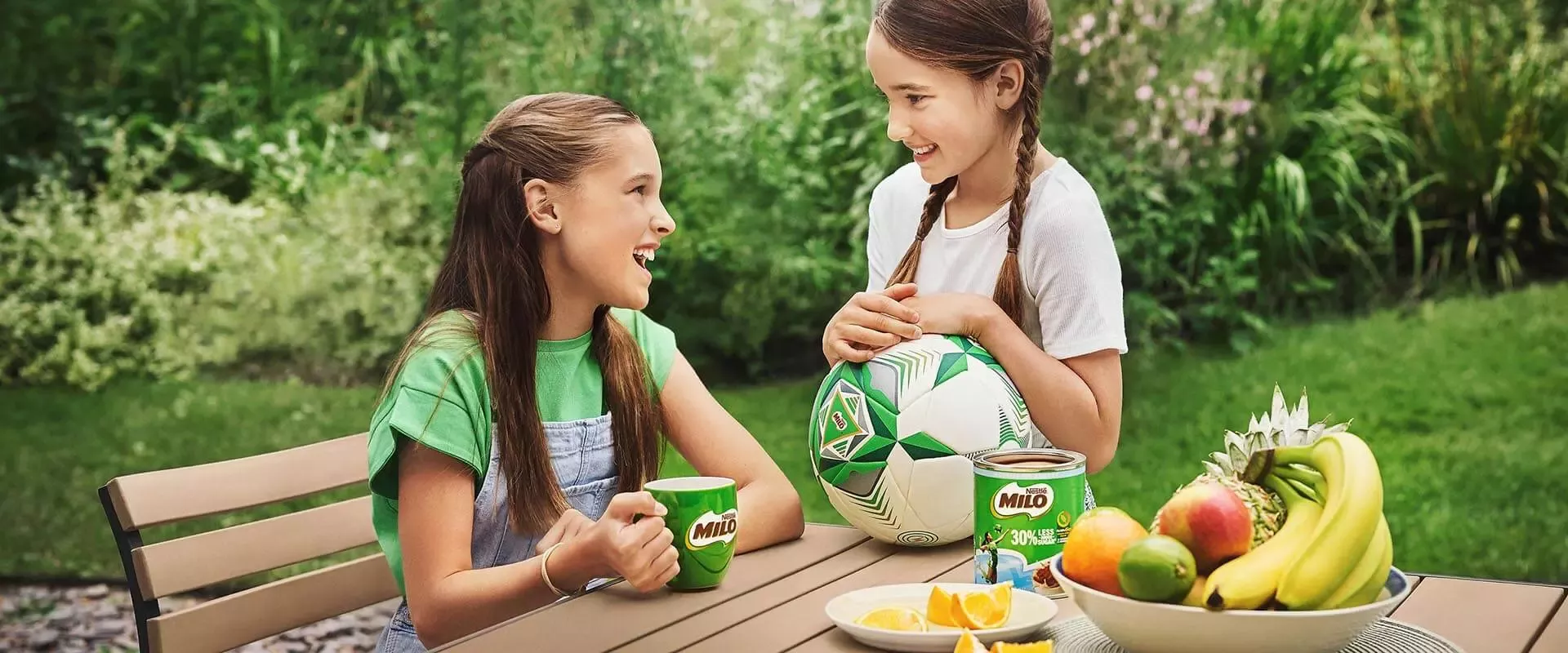 Two little girls talking and drinking Milo 