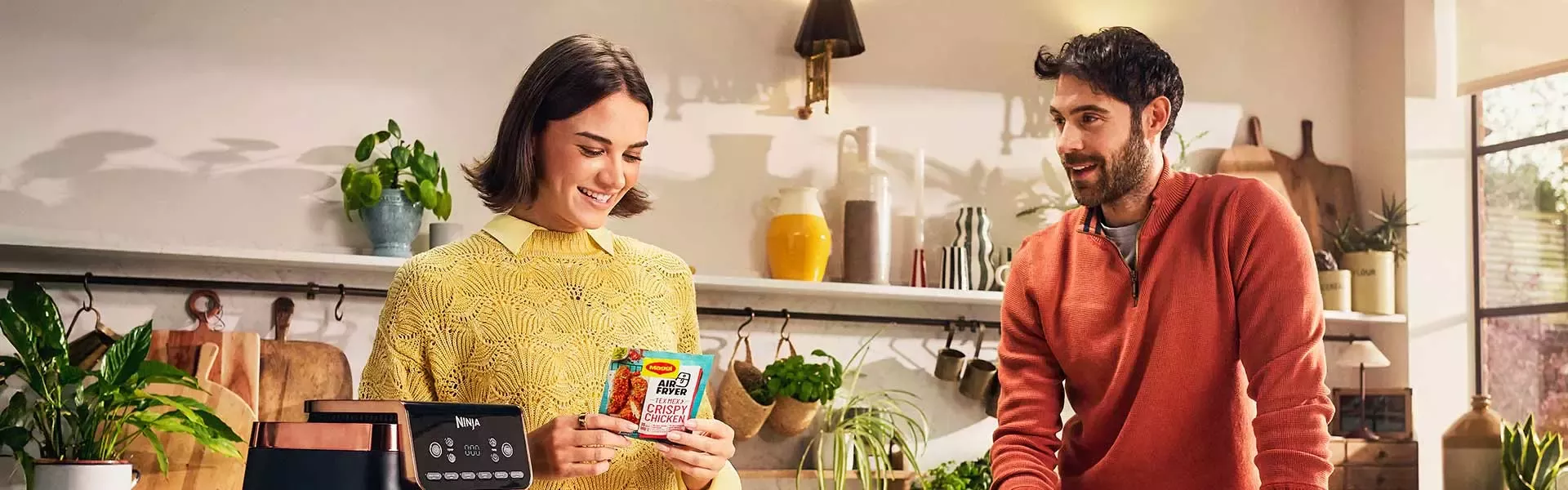 Two people preparing a meal in a kitchen with an air fryer and fresh vegetables on the counter