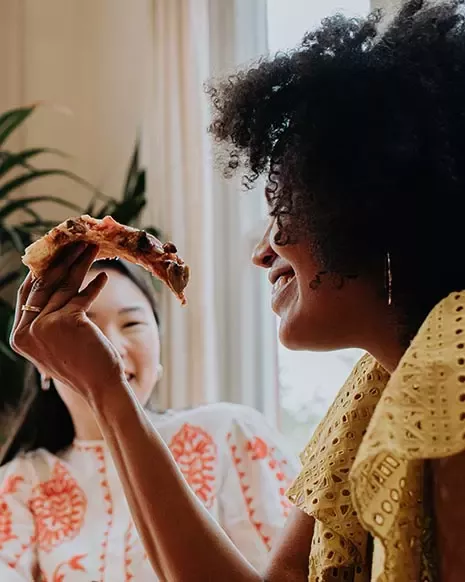 young women having a slice of pizza
