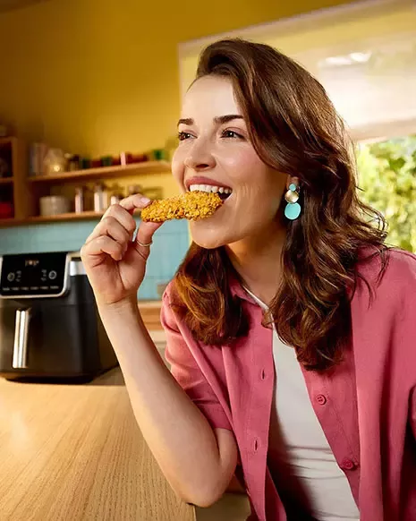 Person enjoying a crispy air fryer coated snack in a modern kitchen