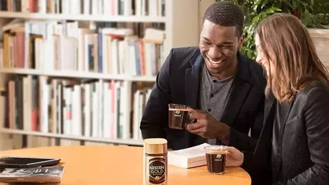A man and a woman drinking coffee in a meeting room