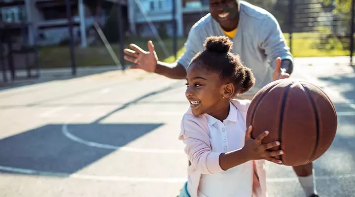 child and adult playing basketball