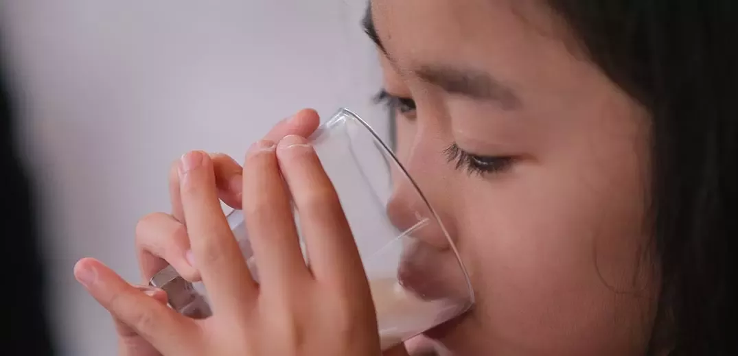 the little girl is drinking the Bear brand milk
