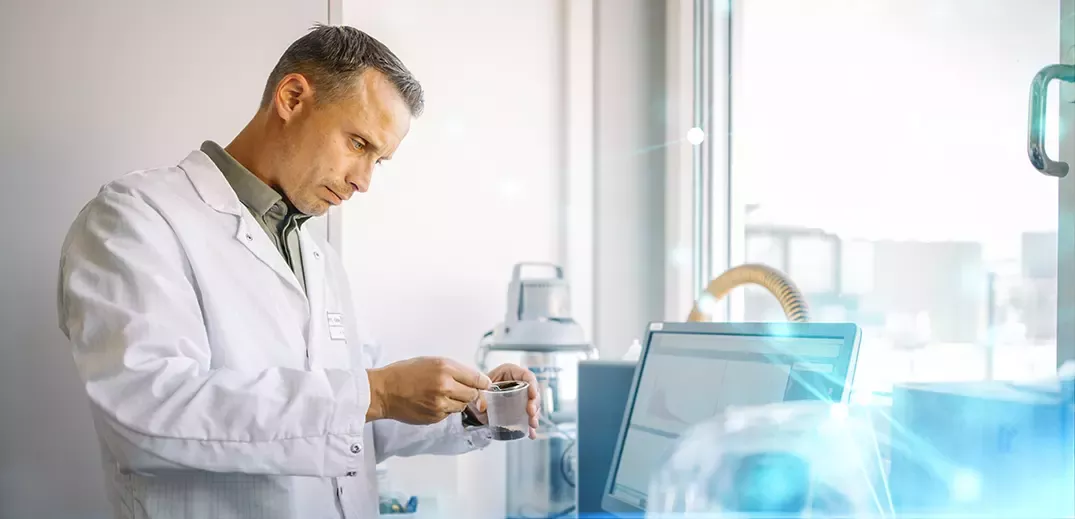 Scientist in a lab coat holding a glass of coffee beans in a lab room