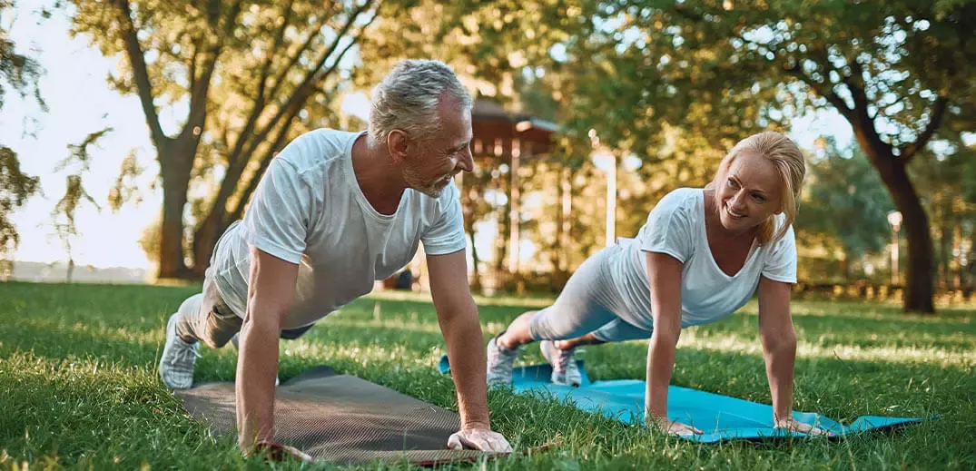 man and woman are doing a workout in the park