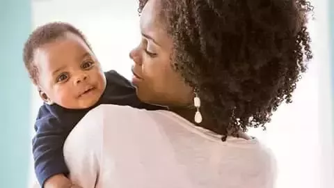 Person holding a baby indoors.