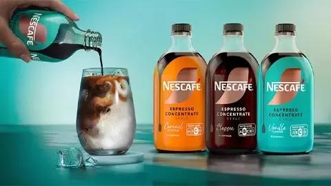 Nescafé Espresso Concentrate bottles beside an iced coffee glass as espresso concentrate is poured