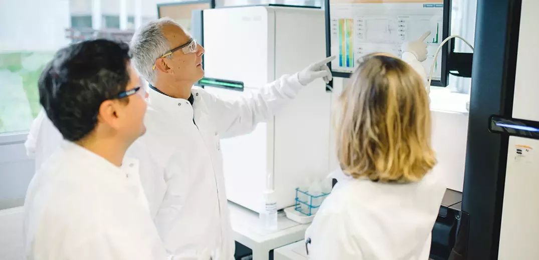 Researchers analyzing data on laboratory screens while operating advanced scientific equipment