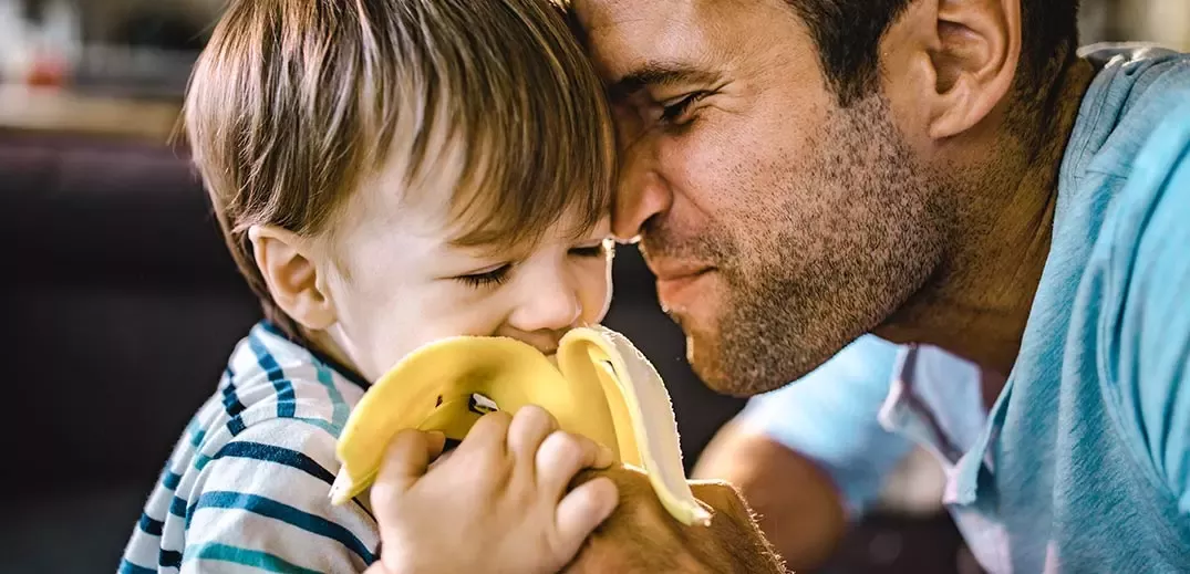 Dad feeding son banana