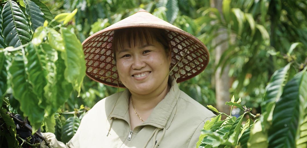 Coffee farmer standing among coffee plants on a regenerative agriculture farm in Vietnam